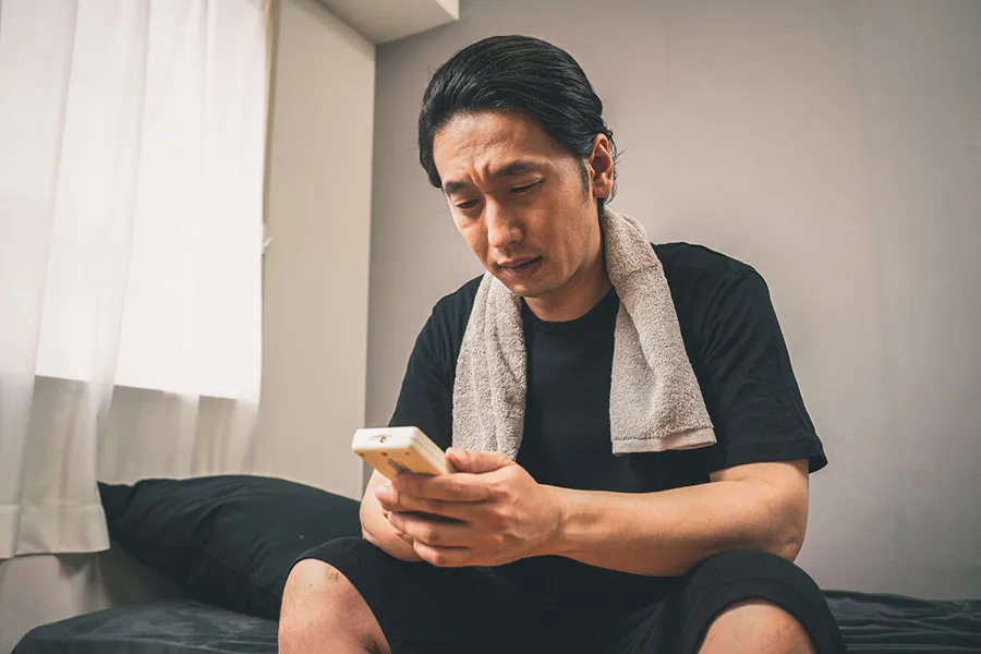 ベッドでうつむいている男性