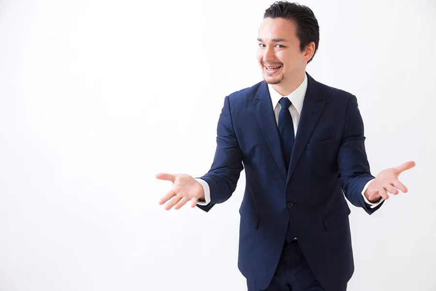 笑顔で両手を広げるスーツの男性