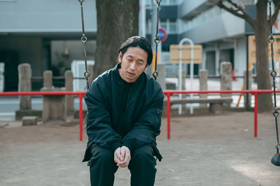 ブランコに座って悲しんでいる男性