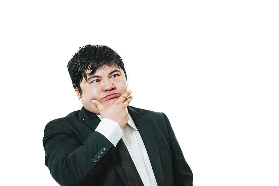 考え事をするスーツの男性